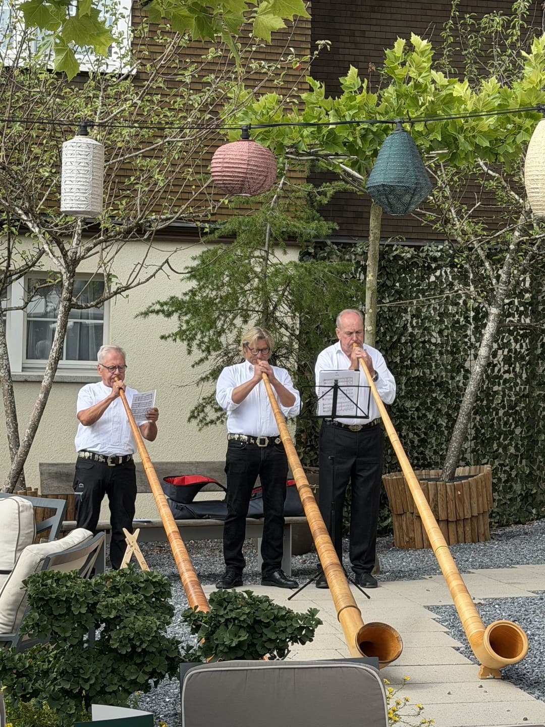 Three alphorn players in the hotel garden
