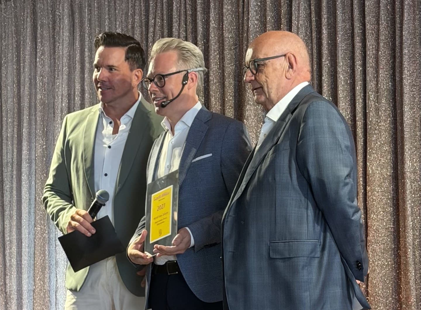 Sven Epiney, Jan Schoch and Urs Heller on stage with the Hotel of the Year 2027 plaque