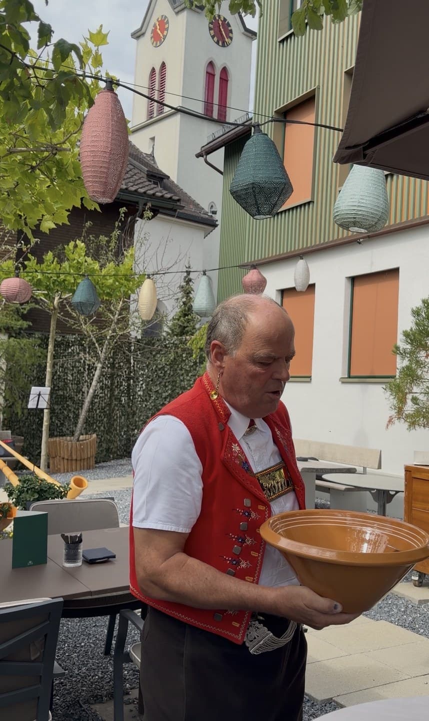 A man in Appenzell dress holding an earthenware bowl for Talerschwingen